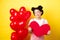 Happy Valentines day. Silly and beautiful asian woman smiling dreamy, showing red heart, imaging romantic date with