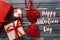 happy valentines day text sign card. stylish red present and heart ribbons flat lay on black rustic wooden background. concept.