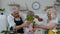 Happy vegan senior couple dancing with granddaughter child while cooking vegetables in kitchen