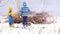 Happy village children in bright and warm clothes play around campfire from branches against gray fence in garden. Children are ha