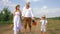 Happy village family on nature, mother, father and child goes with little dog in basket on country road