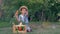 Happy village kid eats carrot and shows thumbs up sits near wood crate with fresh vegetables at garden