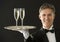 Happy Waiter Carrying Serving Tray With Champagne Flutes