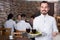 Happy waiter taking care of adults at cafe table