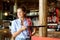 Happy waitress standing at the bar holding drinks