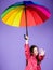 Happy walk under umbrella. Enjoy rain concept. Kid girl happy hold colorful rainbow umbrella. Rainy weather with proper