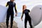 Happy watersport man and woman with SUP paddle boards going to sea, in wetsuit