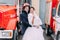 Happy wedding couple posing near big red fire truck. Groom in fireman\'s helmet