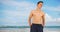 Happy white guy standing relaxed at cloudy beach.