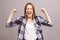 Happy winner! Close-up of emotional young attractive woman with keeping hands in fists, isolated on grey background. Surprised
