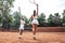 Happy winner! Full length rear view of a woman tennis trainer and sporty girl child on court. Tennis coach and little player