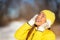 Happy winter woman enjoying cold with yellow hat protecting ears, gloves, coat for frost protection. Asian girl smiling