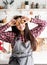 Happy woman in apron holding star shaped cookies in front of her eyes on home kitchen background