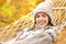 Happy woman in autumn looking at camera on hammock