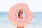 Happy woman on the beach playing with an inflatable donut ring. Summer holidays and vacation concept