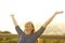 Happy woman on a bench raising arms celebrating life