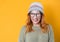 Happy woman blinks one eye, isolated on yellow background. Studio shot of cheerfully blond young girl