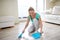 Happy woman with brush and dustpan sweeping floor