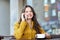 Happy woman calling on smartphone at city cafe