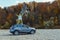 happy woman at car roof enjoying the view of autumn river in carpathian mountains
