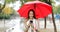 Happy woman checking phone under the rain