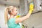 Happy woman cleaning cabinet at home kitchen