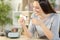 Happy woman cleaning eyeglasses with tissue at home