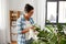 Happy woman cleaning houseplant at home