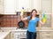 Happy woman cleaning kitchen. Beautiful girl with cleaning spray
