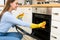 Happy woman cleaning kitchen furniture using sprayer and rag