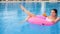 Happy woman With Colorful beverage into arm floating on inflatable ring in pool and giving thumbs up