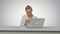 Happy woman is dancing on her own using smartphone at work place on white background.