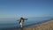 Happy woman dancing at sea shore. Playful girl turning around on beach