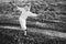 Happy woman in a dress dances barefoot on a muddy field, holding reeds in her hands