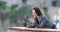 Happy woman drinking and using phone in a balcony