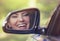 Happy woman driver looking in car side view mirror laughing