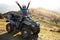 Happy woman driver in protective helmet enjoying extreme riding on ATV quad motorbike in summer mountains at sunset