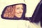 Happy woman driver reflection in car side view mirror