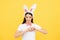 Happy woman in easter bunny ears with heart symbol shape with hands. Funny face. Girl rabbit studio isolated portrait.