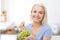 Happy woman eating grapes on kitchen
