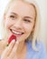 Happy woman eating strawberry at home