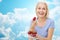 Happy woman eating strawberry over sky