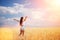 Happy woman enjoying the life in the field Nature beauty, blue sky and field with golden wheat. Outdoor lifestyle. Freedom concept