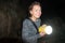 Happy woman explorer holds a flashlight while caving and spelunking underground at Lava Beds National Monument in California