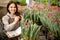 Happy woman farmer carrying box with fresh growing tulips working at industrial greenhouse