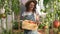 Happy woman farmer in hat dancing with the produce from the tomato garden. Gardener holds wooden box with tomatoes