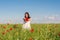 Happy woman in a flowering poppy field outdoors with a poppies bouquet