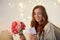 Happy woman with flowers and greeting card at home