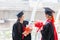 Happy woman graduate hand holding flower bouquet at graduate ceremony, Student graduating school with a cap and gown