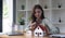 Happy woman hand holding magnifying glass and looking at house model, house selection, real estate concept.